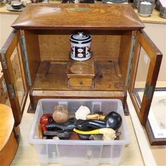 A group of Victorian and later meerschaum and clay pipes with an Edwardian oak smokers cabinet